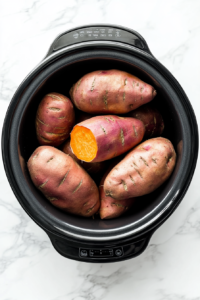 This image shows several sweet potatoes stacked inside a slow cooker, ensuring even heat distribution for a perfectly baked texture.