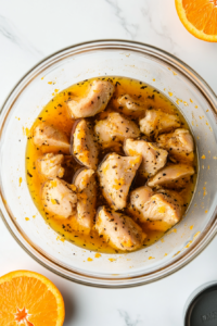 This image shows raw chicken pieces marinating in a bowl with soy sauce, garlic, and other seasonings to enhance the flavor before frying.