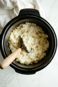 This image shows mashed potatoes being prepared with a hand masher, turning the potatoes into a smooth, creamy texture.