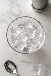 This image shows a mixing glass filled with ice, preparing the base for a perfectly chilled Vesper cocktail.