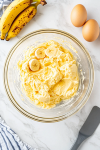 mixing-mashed-bananas-and-eggs-into-the-banana-bread-batter