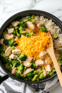 This image shows vibrant green broccoli florets being added to the cooked rice in a pot, combining freshness with flavor.