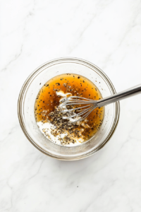 This image shows a creamy mixture of cream, chicken broth, minced garlic, salt, and pepper being stirred together in a mixing bowl, creating a rich and flavorful sauce for scalloped potatoes.