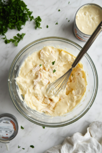 This image shows creamy sauce ingredients being blended together in a bowl, forming a rich and smooth mixture for the Company Chicken Casserole.