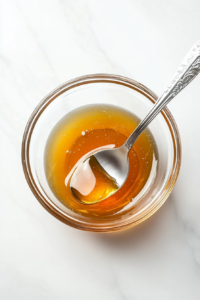 This image shows honey and melted butter being whisked together in a small bowl, creating a sweet and rich glaze for the poppers.