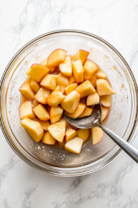 This image shows sliced apples being tossed with the cornstarch mixture, ensuring the apples are evenly coated before being placed in the crockpot.