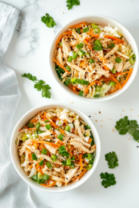 This image shows a beautifully plated Chinese chicken salad, garnished with toasted sesame seeds and fresh herbs, ready to be enjoyed as a light and flavorful meal.