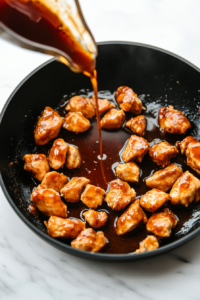 This image shows the golden honey bourbon sauce being poured over the seared chicken, coating it in a glossy glaze.