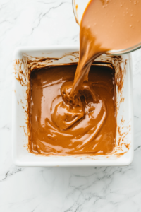 This image shows the smooth cake batter being poured evenly into a greased baking pan, preparing it for the cinnamon swirl topping.