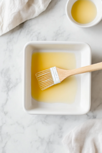 This image shows an oven being preheated and a baking pan being greased with butter or cooking spray, ensuring the cake does not stick during baking.