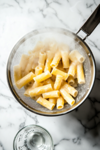 This image shows a cup of starchy pasta water being poured into a container, an essential step for creating a silky, well-emulsified sauce for the creamy shrimp rigatoni.