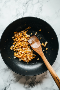 This image shows chopped onions and minced garlic being sautéed in butter until fragrant, adding depth and aroma to the dish.