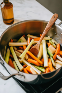 This image shows onions, carrots, and celery being sautéed in a pot with hot oil, releasing their aroma and forming the base of the shredded chicken soup.