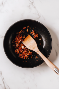 This image shows chopped onions being sautéed in a pan until soft and fragrant, adding depth of flavor to the Bang Bang Chicken and Shrimp recipe.