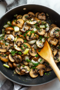 This image shows vegetables, including onions and mushrooms, being sautéed in a pan, preparing the base for the Crockpot Stuffing.