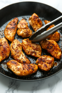 This image shows chicken pieces sizzling in a pan, developing a crispy golden-brown crust for added flavor and texture.