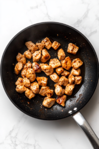 This image shows chopped onions and minced garlic being added to the skillet, enhancing the aroma and flavor of the dish.