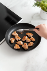 This image shows seasoned chicken cooking in a hot skillet, achieving a golden brown exterior.