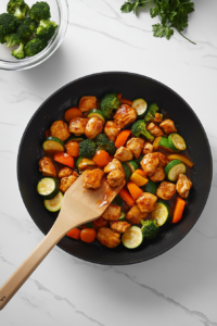 This image shows marinated chicken pieces sizzling in a hot pan, developing a golden-brown sear and locking in the flavors for the Chicken and Vegetables Stir Fry.