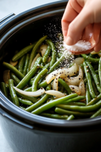 This image shows salt and pepper being sprinkled over the cooked green beans, enhancing their flavor before serving.