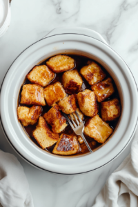 This image shows the finished crockpot French toast served in a bowl, with golden, slightly crispy bread pieces ready to be enjoyed as a warm, comforting breakfast.