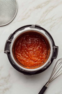 This image shows the remaining jerk sauce simmering in the Instant Pot, reducing into a thick, flavorful glaze.