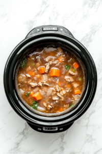 This image shows the crockpot filled with slowly simmering broccoli and other ingredients, allowing the flavors to blend and develop into a creamy broccoli cheese soup.