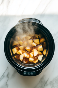 This image shows apples slowly cooking in a slow cooker, breaking down into a soft and fragrant mixture for homemade applesauce.