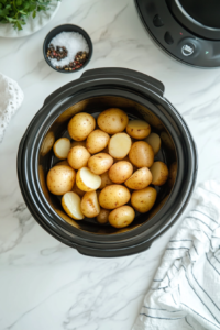 This image shows potatoes cooking in the slow cooker, softening up to become perfect for mashing.