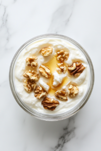 This image shows a beautifully plated bowl of Greek yogurt with honey and walnuts, ready to be enjoyed as a healthy and flavorful dessert.