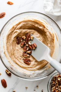 This image shows chopped pecans being folded into the pie batter, adding a nutty crunch and rich depth of flavor to the crustless apple pie.