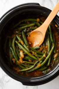 This image shows the green beans being stirred to evenly distribute the seasonings, then served with a garnish of fresh cilantro for a bright, fresh finish.