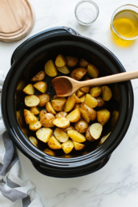 This image shows the crockpot potatoes being stirred halfway through cooking, with additional seasonings being added to enhance the flavor.