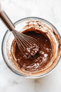 This image shows a mixing bowl where wet and dry ingredients are being combined to form a thick, smooth cornbread batter.