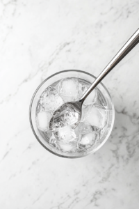 This image shows a bartender stirring the Vesper cocktail in a mixing glass to ensure a smooth and well-balanced flavor.