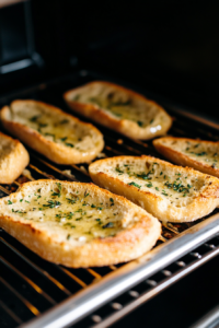 this-image-shows-garlic-bread-slices-in-the-oven-turning-golden-brown-with-crispy-edges-ready-to-be-served-alongside-creamy-shrimp-rigatoni