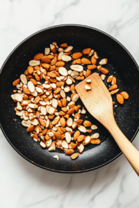 This image shows almonds being toasted in a pan to bring out their nutty flavor, ready to be used as a crunchy garnish for the tuna salad.