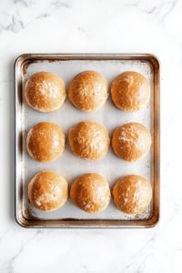 This image shows sandwich buns being toasted on a pan until golden brown, adding a warm and slightly crispy texture to the Honey Pepper Pimento Chicken Sandwich.