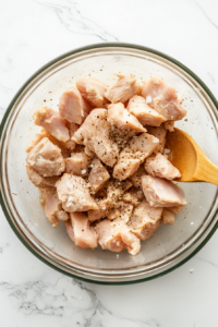 This image shows chicken pieces being tossed in a spice mix to ensure every piece is evenly coated with flavor.