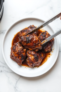 This image shows cooked jerk chicken being removed from the Instant Pot and placed on a plate, ready for the next step.