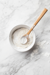 This image shows sticky bread dough being scraped from the bowl onto a floured surface, preparing it for shaping.