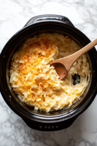 This image shows the hash brown mixture being carefully transferred into a greased slow cooker, ready to cook into a delicious casserole.