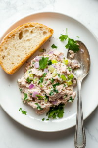 This image shows a top-down view of a freshly prepared tuna salad, served in a bowl and ready to be enjoyed, with optional garnishes for added flavor.