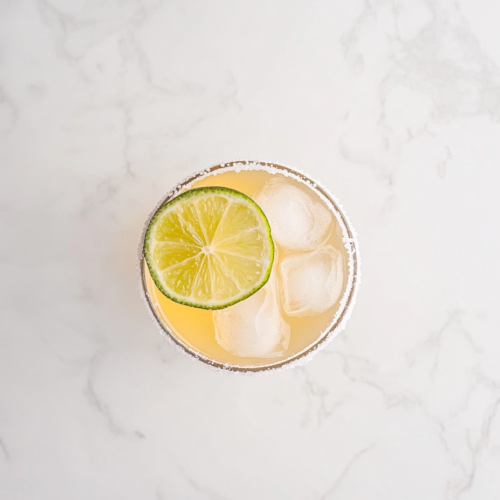 This image shows a refreshing vodka margarita served in a chilled glass filled with ice, garnished with a slice of lemon, and ready to be enjoyed.