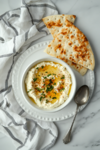 This image shows the whipped feta dip beautifully presented alongside crispy bread and crackers, ready to be enjoyed as a flavorful appetizer.