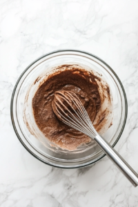 This image shows eggs, milk, and warm spices being whisked together in a bowl to create the rich, custardy mixture for the French toast.