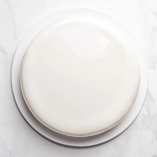 This image shows a creamy and smooth White Mirror Glaze Cake, beautifully set and ready to be served as a stunning dessert.