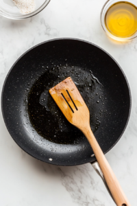 This image shows a skillet being wiped clean after cooking the vegetables, ensuring a fresh cooking surface for the marinated chicken.