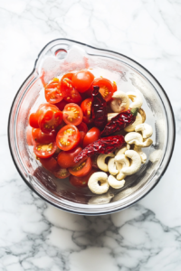 This image shows cashews and ripe tomatoes being blended into a smooth and creamy puree, forming the rich and flavorful base for the chicken gravy.