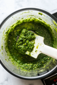 This image shows a food processor blending the mixture, with a spatula inside to help incorporate all the ingredients into a smooth chutney paste.